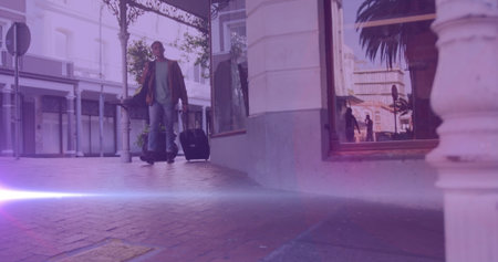 Image of coloured lights over biracial man walking to work, wheeling suitcase in street. walk to...
