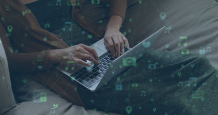 Image of network of connections with social media icons over caucasian women using laptop. Social media and communication concept digitally generated image.の写真素材