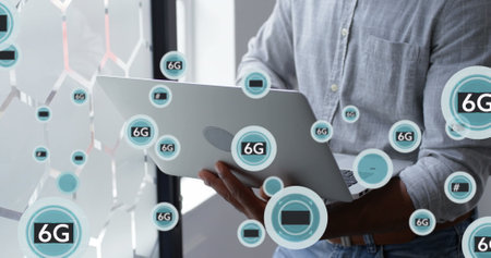 Image of symbols and 6g text in circles, midsection of african american man working on laptop. Digital composite, multiple exposure, signs, office, telecommunication and technology concept.の写真素材