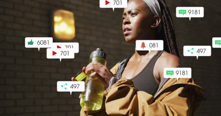Image of icons, changing numbers, african american female athlete drinking water. Digital composite, multiple exposure, business, growth, technology and social media reminder concept.の写真素材