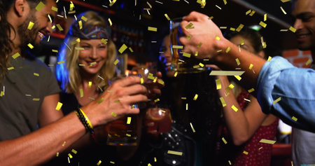 Friends holding drinks, celebrating together at lively bar. Enjoying a festive mood, surrounded by...