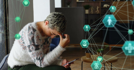 Image of connected icons globes over stressed caucasian woman using smartphone. Digital composite,...