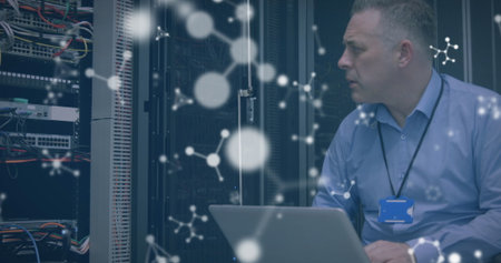 Image of molecules over stressed caucasian man working on laptop in server room. computers, science...