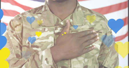 Image of yellow and blue hearts over african american male soldier singing anthem on usa flag. Ukraine crisis and international politics concept digitally generated image.の写真素材