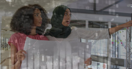 Two young female business creatives discussing plans and looking at graphs and statistics. the data processing and business graphs are animatedの写真素材