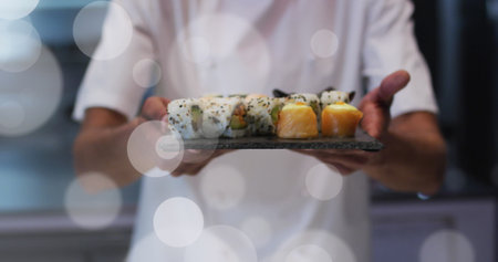 Image of white spot lights over male chef serving sushi. Food, leisure, free time and celebration concept digitally generated image.の写真素材