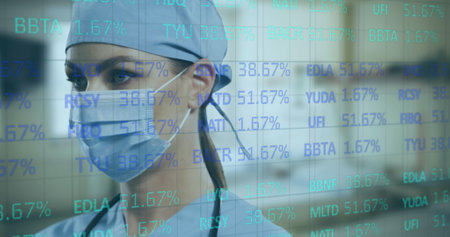 Image of financial data processing and female doctor in face mask. Covid 19 pandemic, medicine, healthcare, finance, computing and data processing concept digitally generated image.の写真素材
