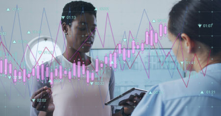 Image of multiple graphs with changing numbers, diverse female coworkers discussing reports. Digital...