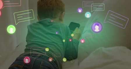 Image of social media icons over rear view of caucasian boy using smartphone on couch at home....