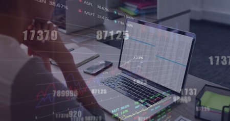 Image of stock market data processing and numbers over biracial woman using laptop at office. Global...