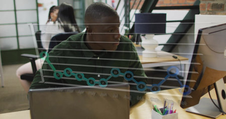 Image of graph over african american man working on computer in office. Digital composite, multiple...