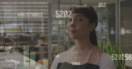Image of statistical data processing against portrait of biracial woman smiling at office. Computer interface and business data technology conceptの写真素材