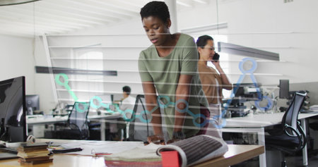 Image of month names and graph over african american woman working on blueprint in office. Digital composite, multiple exposure, report, business, profession and technology concept.の写真素材