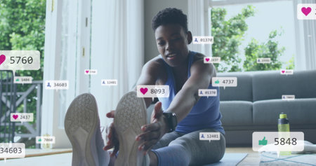 Image of social media icons and numbers over african american woman exercising at home. Global social media, computing and data processing concept digitally generated image.の写真素材