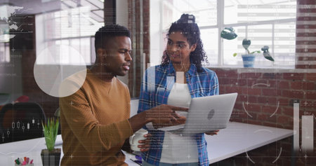 Image of statistical data processing over diverse man and woman discussing over laptop at office. Computer interface and business data technology conceptの写真素材