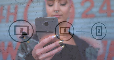 Image of technological icons over Caucasian woman with pink hair using smartphone. Digital online security computer interface concept digitally generatedの写真素材