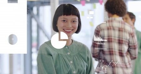 Image of graphs, map, flowchart, cloud in laptop over smiling biracial woman standing in office. Digital composite, multiple exposure, report, business, global, cloud computing and technology.の写真素材