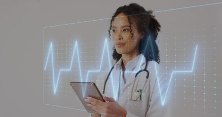 Image of heart rate monitor over african american female doctor using digital tablet at hospital. Medical healthcare technology conceptの写真素材