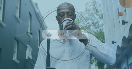 Middle-aged African American in white shirt drinks coffee, checks smartphone. He has short black hair and is walking down city streetの写真素材