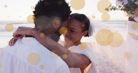 Image of light spots over african american couple getting married on beach. Wedding day, celebration, togetherness and love concept digitally generated image.の写真素材