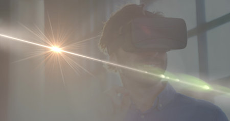 Image of light spots over caucasian man with vr headset. Global business and digital interface concept digitally generated image.の写真素材