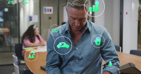 Senior Caucasian male investor looking at virtual business app design. Diverse entrepreneurs working in background, one with tabletの写真素材