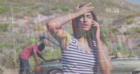 Image of financial data processing over biracial woman talking on smartphone. Global technology, finances and digital interface concept, digitally generated image.の写真素材