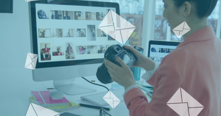 Image of envelopes over biracial female photographer looking at camera while working in office. Digital composite, multiple exposure, message, business and technology concept.の写真素材