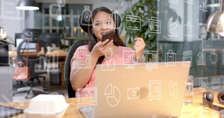 Image of business icons and data processing over biracial businesswoman in office. Global finance,...