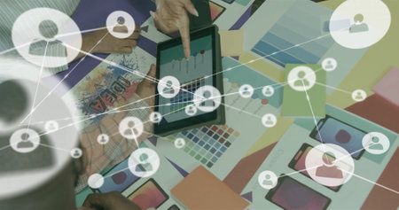 Image of network of connections with icons over diverse colleagues discussing project. Technology, business and digital interface concept digitally generated image.の写真素材