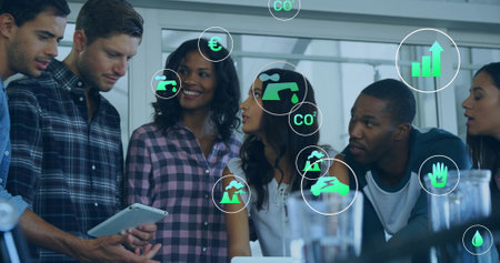 Image of ecology icons over diverse colleagues using tablet in office. Business, technology and digital interface concept digitally generated image.の写真素材