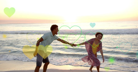Image of hearts moving over diverse couple in love dancing on beach in summer. Love, romance, valentine&#39;s day and vacation concept digitally generated image.の写真素材