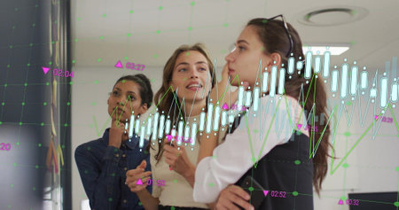 Image of graph processing data over diverse female colleagues brainstorming at casual office. Business, connection, teamwork, digital interface and communication, digitally generated image.の写真素材