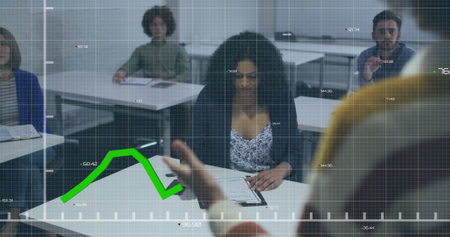 Image of green graphs moving over african american woman taking notes during a presentation....