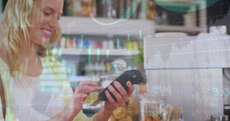 Image of data processing over caucasian woman using credit card to make payment at cafe. Digital payment and business technology conceptの写真素材