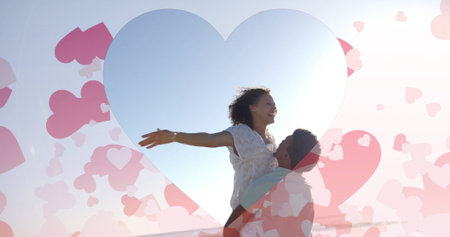 Image of hearts moving over biracial man carrying woman on beach in summer. Love, romance, valentine's day and vacation concept digitally generated image.の写真素材