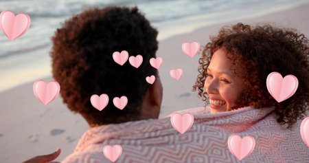 Image of hearts moving over diverse couple in love embracing on beach in summer. Love, romance, valentine's day and vacation concept digitally generated image.の写真素材