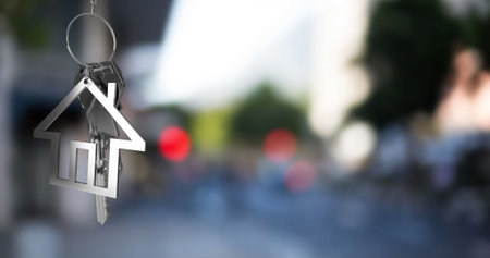 Image of hanging silver house keys against blurred view of city traffic with copy space. Relocation and real estate conceptの写真素材