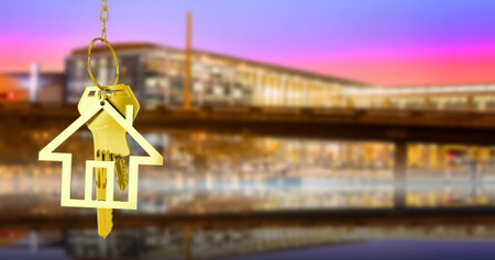 Image of hanging golden house keys against blurred view of night cityscape with copy space. Relocation and real estate conceptの写真素材