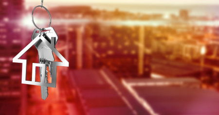 Image of hanging silver house keys against blurred view of cityscape with copy space. Relocation and real estate conceptの写真素材
