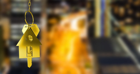 Image of hanging golden house keys against blurred view of night cityscape with copy space. Relocation and real estate conceptの写真素材