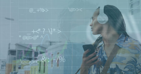 Image of graphs, symbols, biracial man listening to music on cellphone wearing headphone. Digital composite, multiple exposure, report, business, signs and technology concept.の写真素材