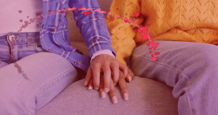 Image of hearts over happy diverse couple holding hands at home. Love, relationship, home and lifestyle concept digitally generated image.の写真素材