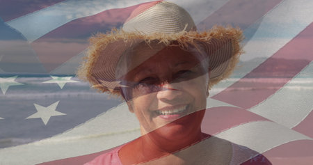 Image of flag of usa over happy senior biracial woman on beach. American patriotism, nationality, summer and diversity concept digitally generated image.の写真素材