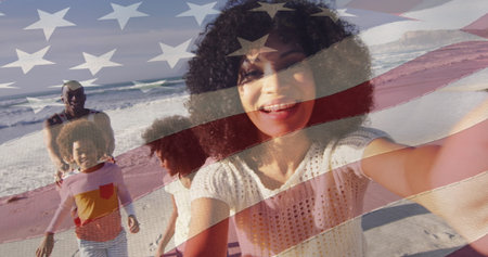 Image of flag of usa over happy african american couple with children on beach. American patriotism,...