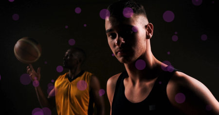 Image of diverse basketball players with ball and spots of light on black background. Sports, competition and movement concept digitally generated image.の写真素材