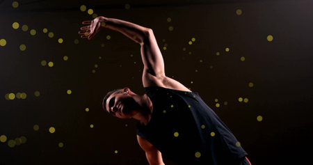 Image of caucasian basketball player stretching and spots of light on black background. Sports, competition and movement concept digitally generated image.の写真素材