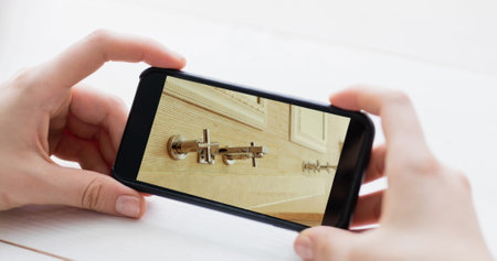 Image of person using smartphone with house bathroom interiors displayed on screen. Online shopping...