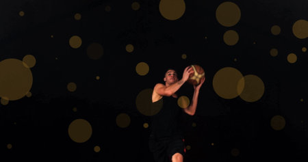 Image of caucasian basketball player throwing ball and spots of light on black background. Sports, competition and movement concept digitally generated image.の写真素材
