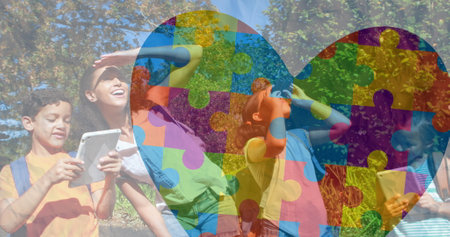 Image of colorful puzzle pieces heart over happy playing children. autism, learning difficulties, support and awareness concept digitally generated image.の写真素材
